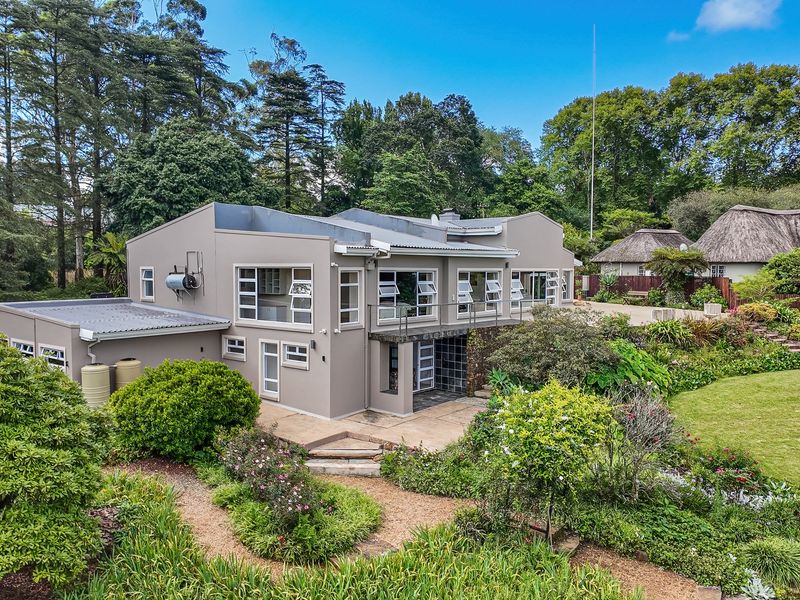 Rear view of a multi-level residence featuring a landscaped garden, paved patio area, and established trees in a tranquil setting.