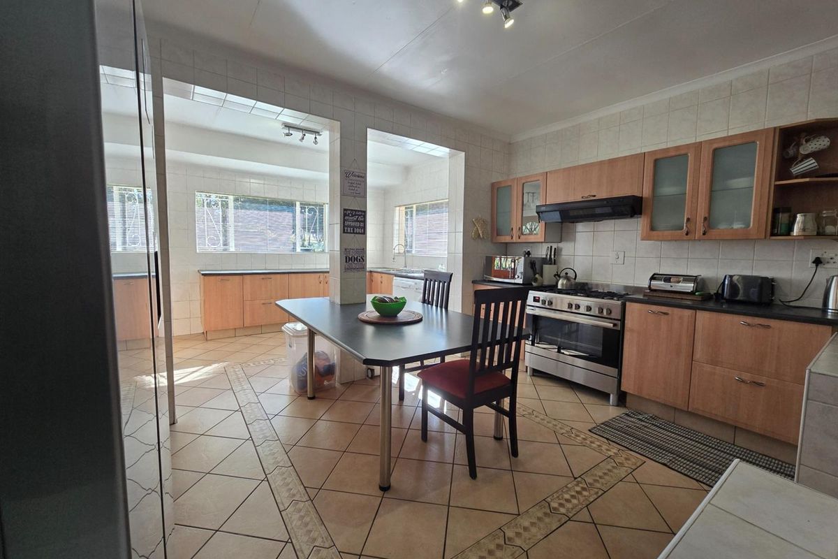 Spacious kitchen featuring wooden cabinetry, tiled flooring, and a gas stove, with an integrated dining area and ample counter space.