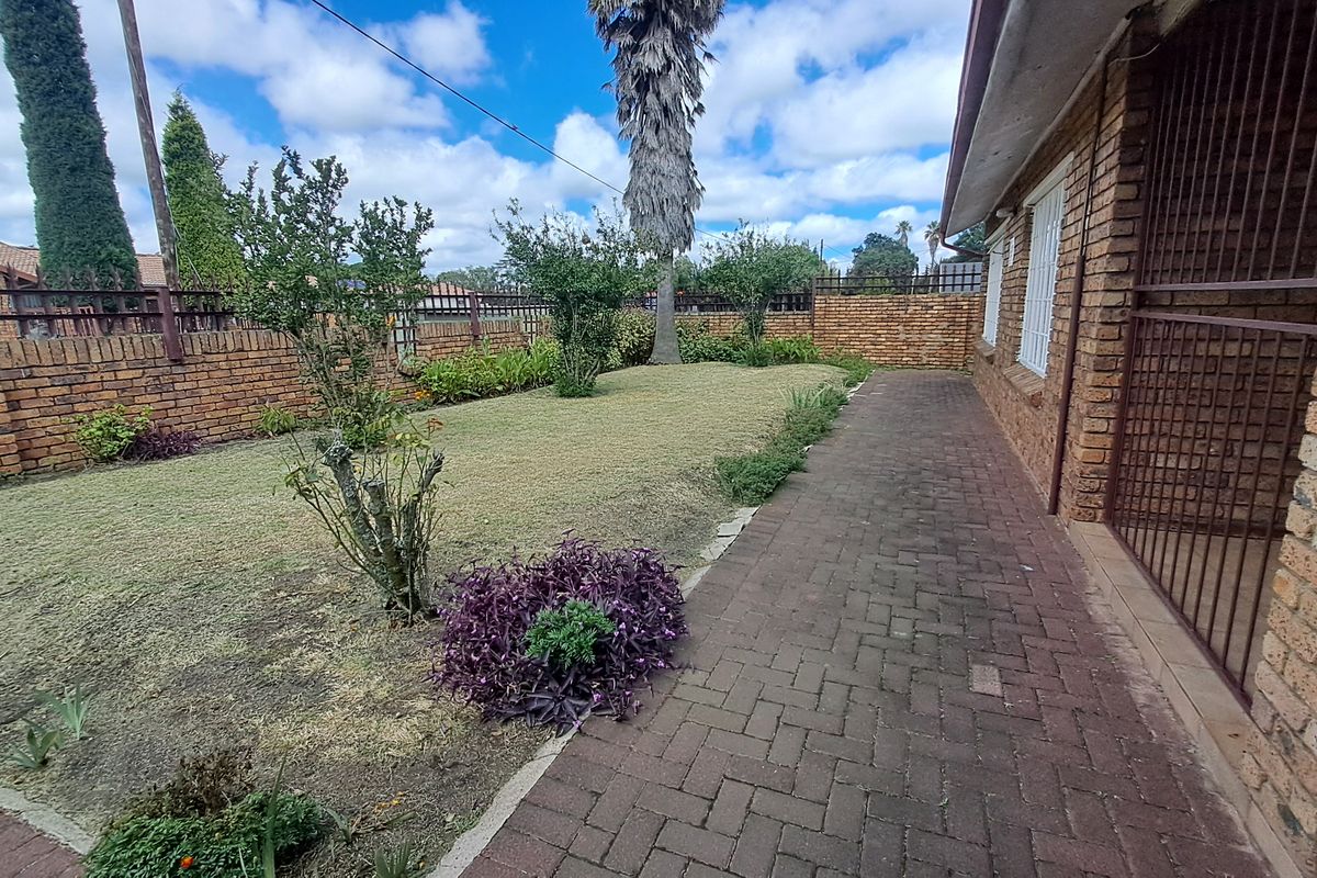 A private rear garden featuring a brick boundary wall, a paved walkway, and established landscaping, providing a secure outdoor space.