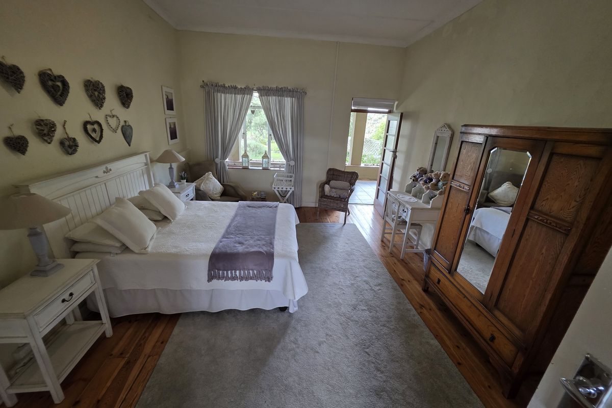 Spacious bedroom featuring original timber flooring, large window with garden views, and direct access to an outdoor patio area.