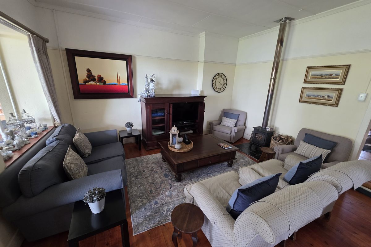 A cozy living room featuring polished timber flooring and a built-in wood-burning fireplace with a stainless steel flue.