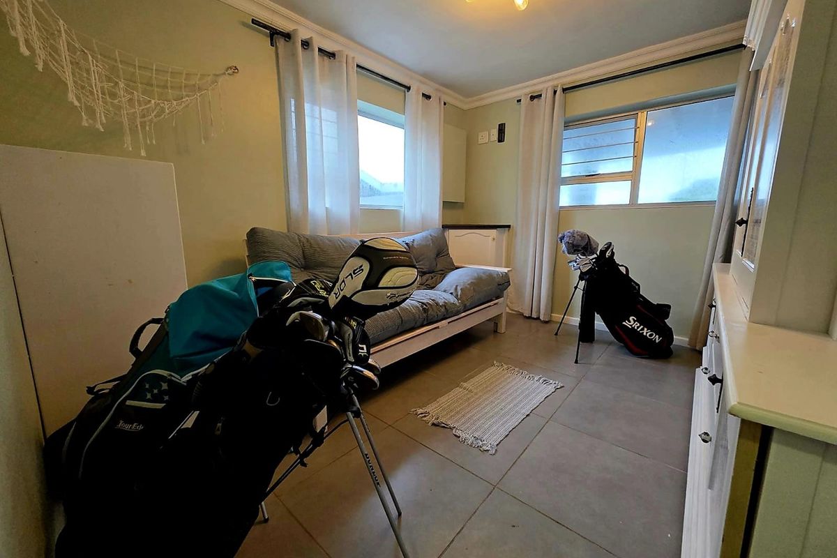 A bedroom featuring tiled flooring, crown molding, and louvered windows, providing a functional space with natural light.