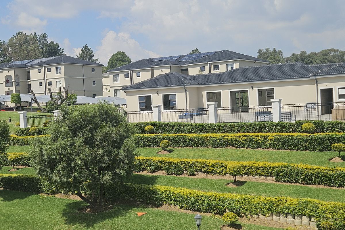 A well-maintained townhouse complex featuring terraced gardens, manicured hedges, and modern buildings with tiled roofs and integrated solar panels.