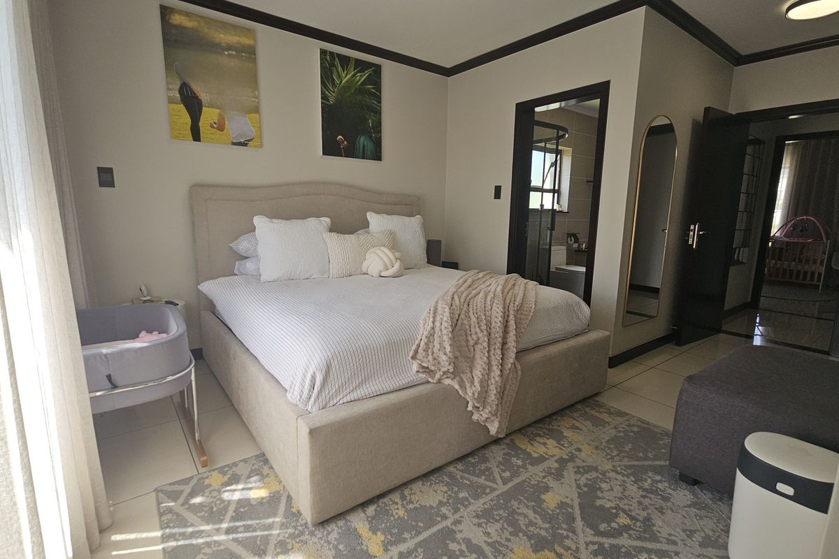 A well-maintained bedroom featuring tiled flooring, crown molding, and direct access to an en-suite bathroom.
