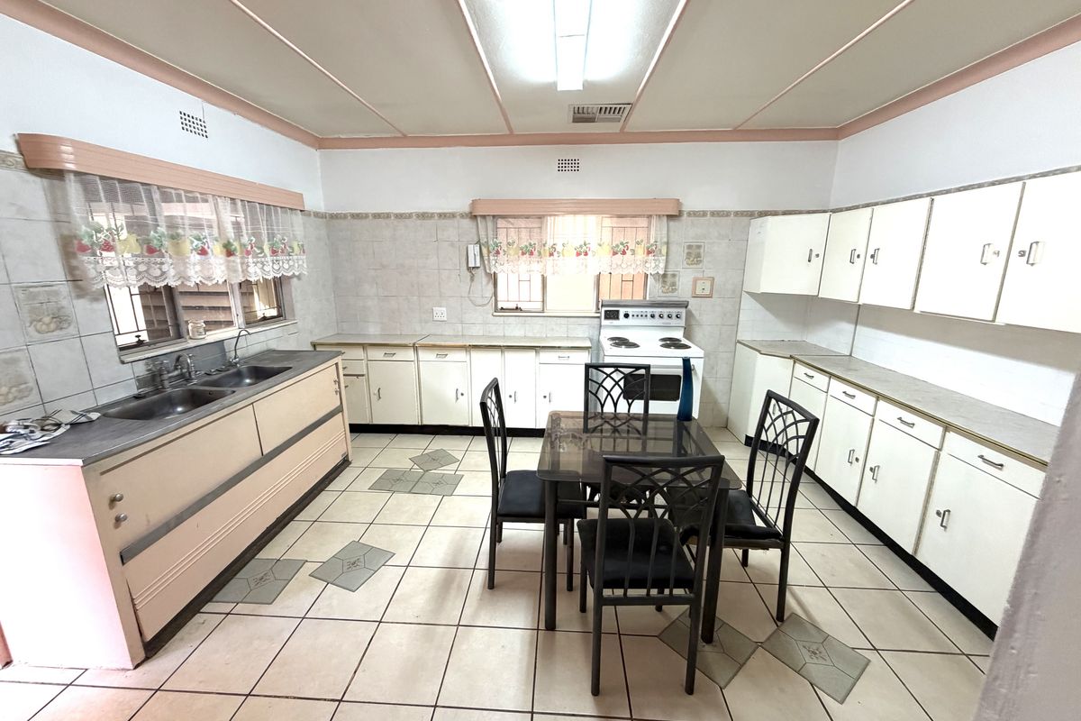 Spacious kitchen featuring extensive built-in cabinetry, tiled flooring, and a dedicated dining area, offering a functional layout with potential for modern updates.