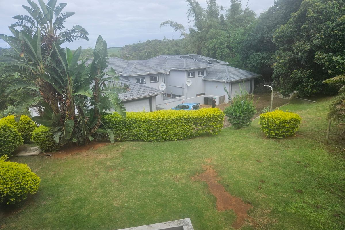 Elevated view of the rear exterior of the townhouse, featuring a tiled roof with solar panels, double garage, and a spacious landscaped garden.