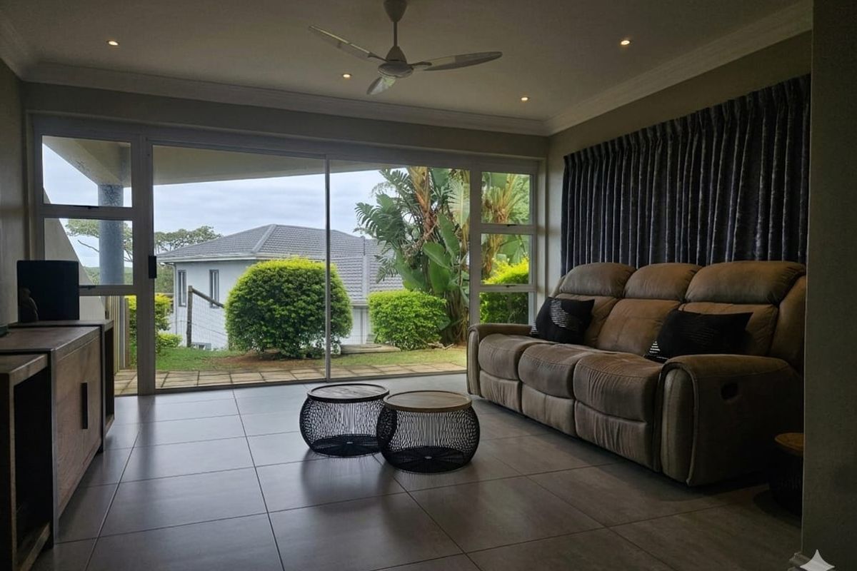 Spacious living room featuring large sliding glass doors that provide natural light and direct access to the garden area, complemented by modern tiled flooring.