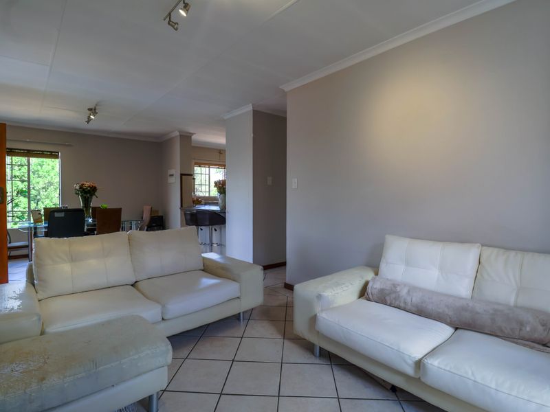 Open-plan living area featuring tiled flooring and neutral wall finishes, seamlessly connecting to the dining space and kitchen area.
