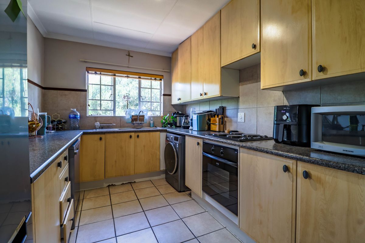 Functional kitchen featuring laminate cabinetry, tiled backsplash, built-in oven, gas hob, and space for a washing machine under the counter.