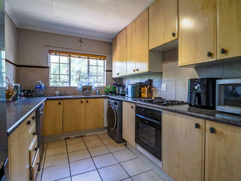 Functional kitchen featuring laminate cabinetry, tiled backsplash, built-in oven, gas hob, and space for a washing machine under the counter.