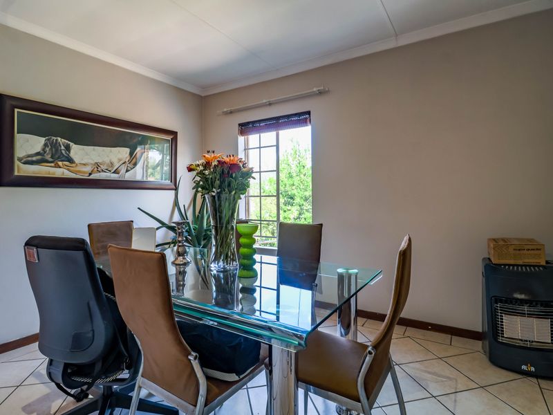 A dining room featuring tiled flooring, a window with security bars, and coved ceiling details, providing a functional space for meals.