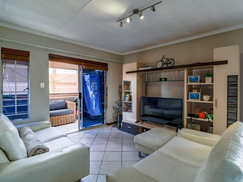 A living room featuring tiled flooring, a built-in shelving unit, and a sliding glass door providing access to an outdoor patio area.