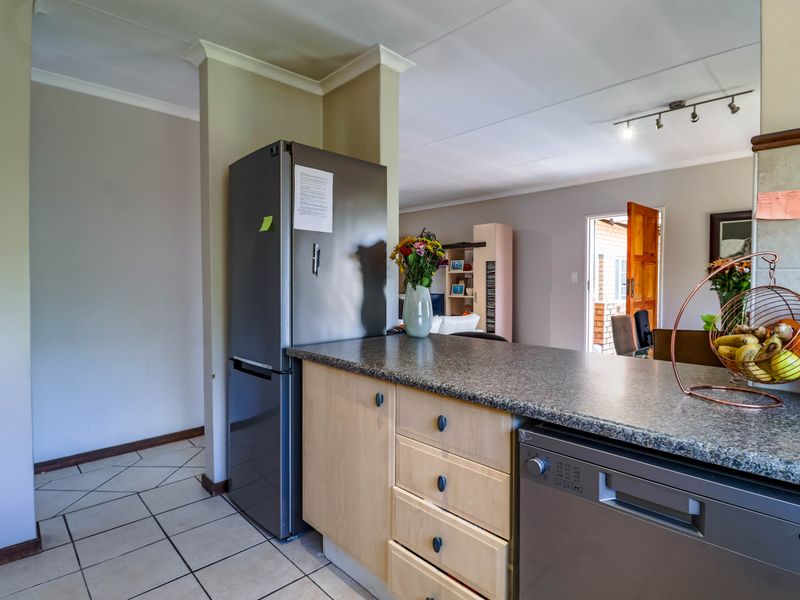 Open plan kitchen area featuring laminate cabinetry, granite countertops, and tiled flooring, seamlessly connecting to the living space.