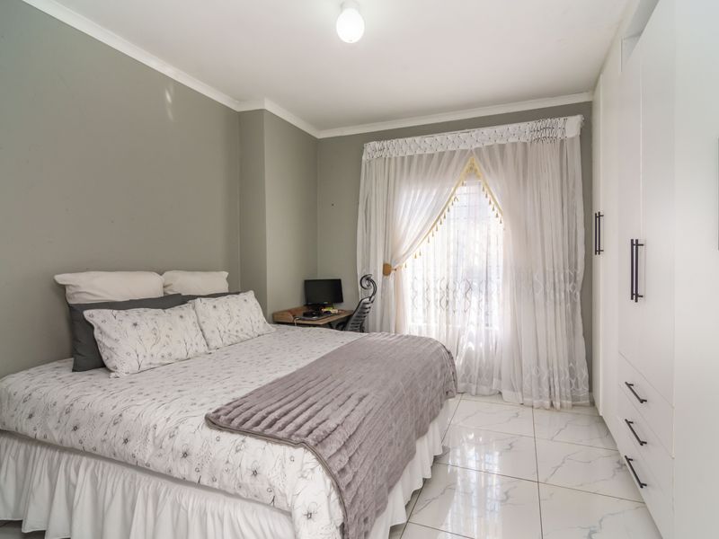 A well-maintained bedroom featuring modern white built-in cupboards, polished marble-look floor tiles, and neutral wall tones.