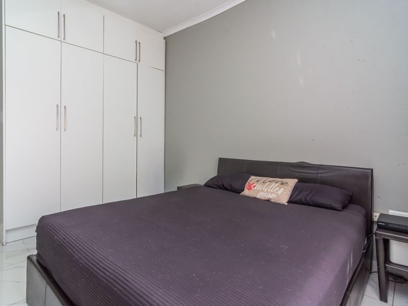 A bedroom featuring built-in cupboards and tiled flooring, providing a functional and neutral space.