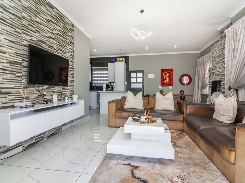 Spacious open-plan living area featuring modern tiled floors, a striking feature wall, and a functional kitchen with built-in cabinetry and island.