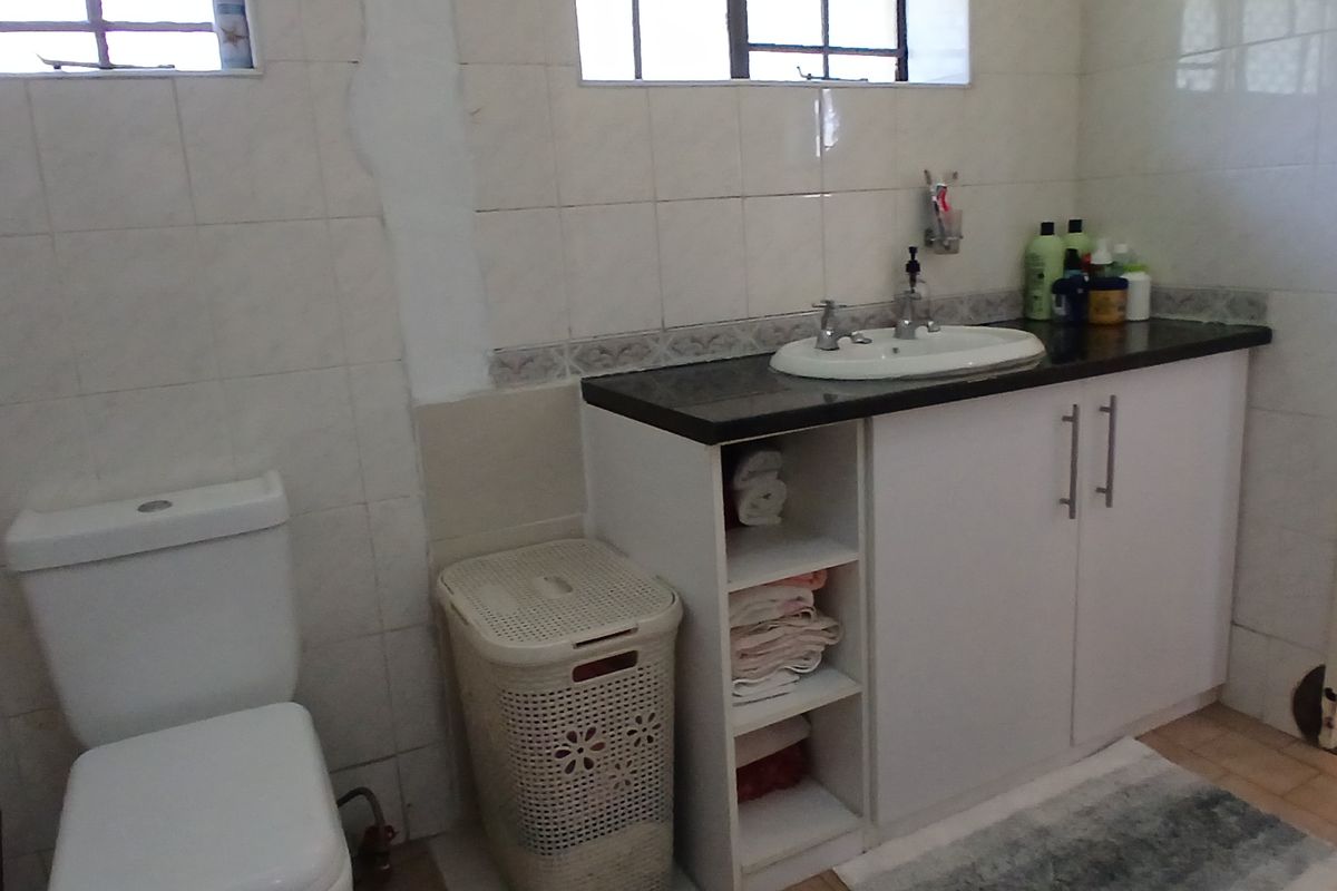 A functional bathroom featuring a vanity with a stone countertop, integrated basin, and wall-mounted toilet with tiled finishes.