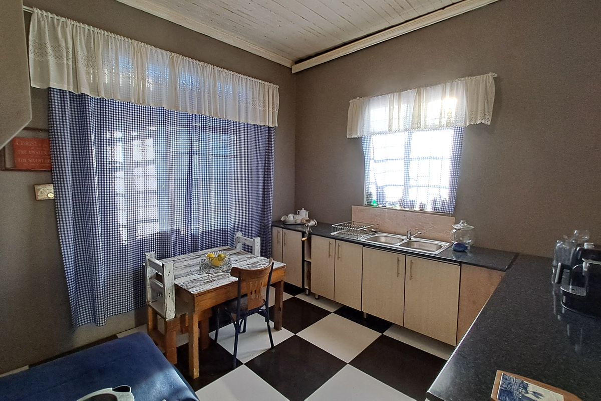 A functional kitchen featuring a double bowl sink, dark countertops, and a distinctive checkerboard tiled floor with timber plank ceiling detail.
