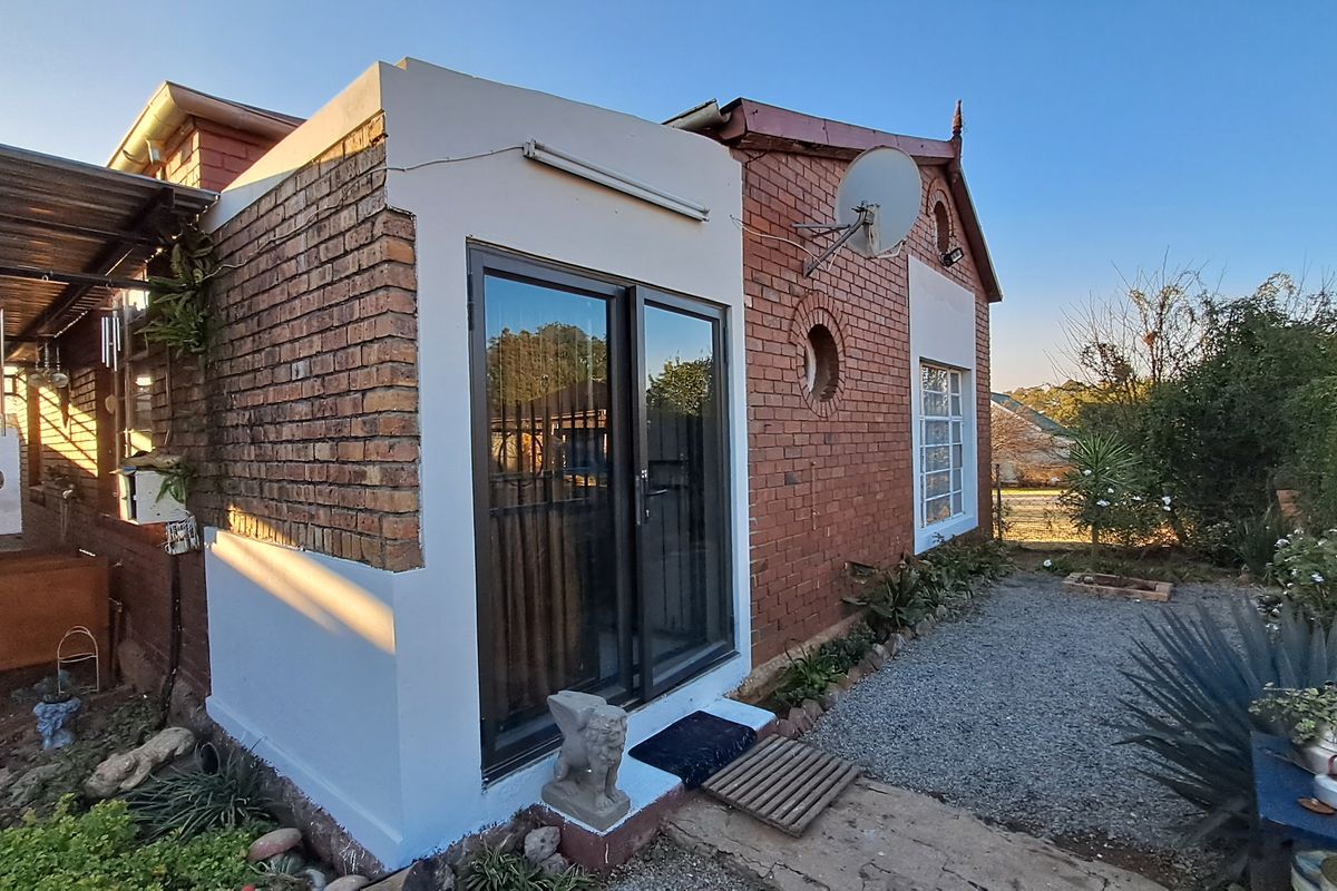 Rear exterior view of the house featuring a brick facade, sliding glass door access, and a gravel garden area.