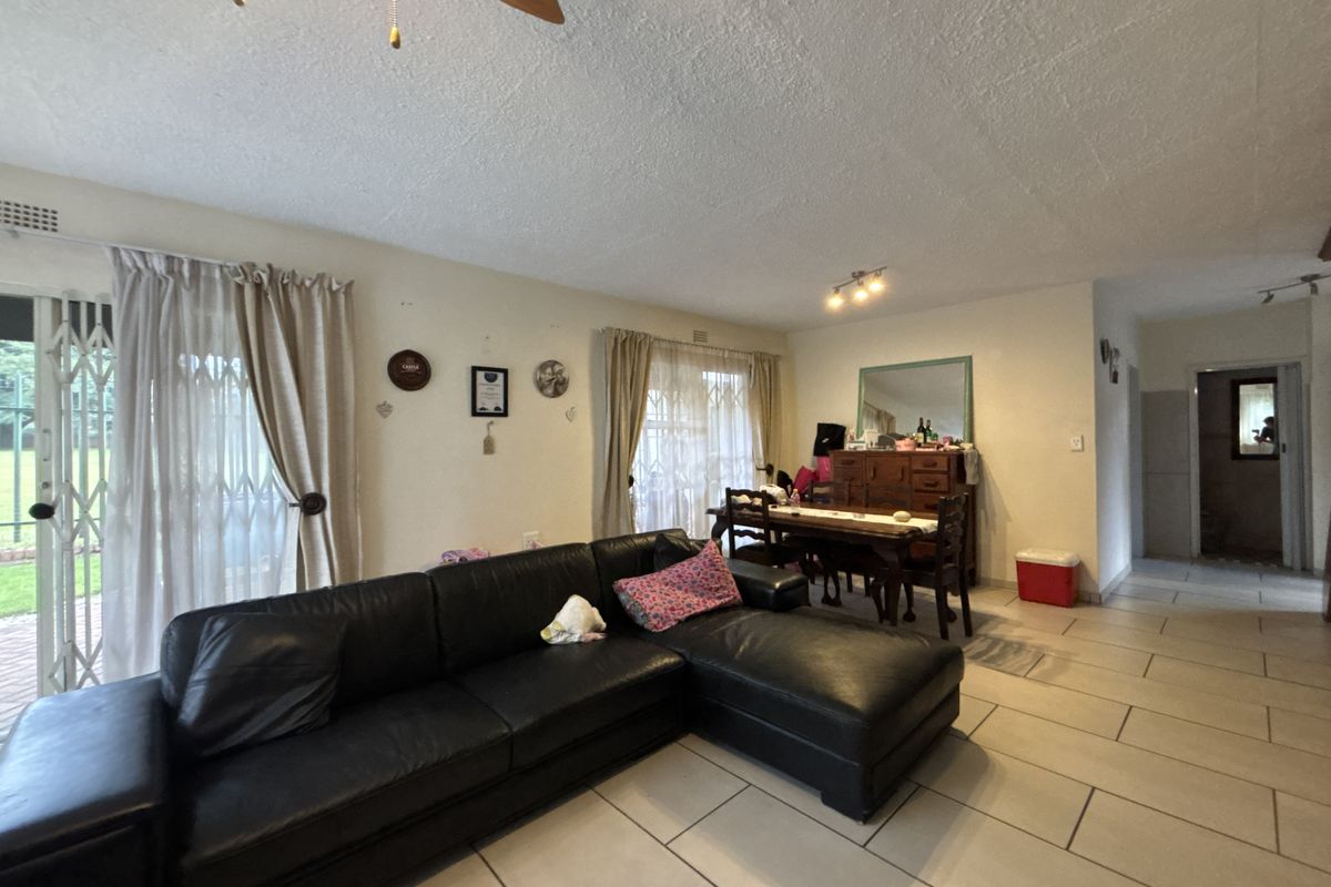 Spacious living area featuring tiled flooring, ceiling fan, and sliding glass doors providing access to the exterior.