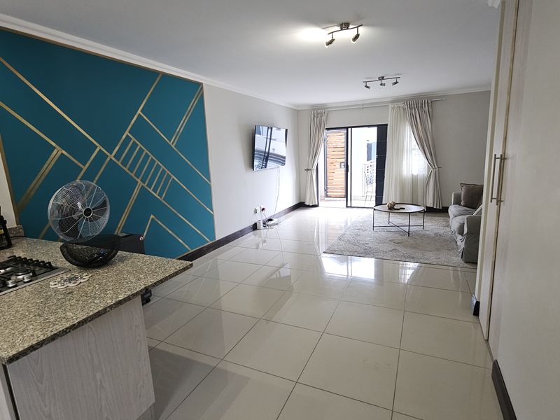 Spacious open-plan living area featuring a modern kitchen with granite countertops, gas hob, and seamless flow to a private balcony through sliding glass doors.