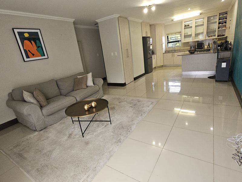 Spacious open-plan living area featuring polished porcelain floor tiles, a modern kitchen with granite countertops, and integrated cabinetry, creating a bright and functional living space.
