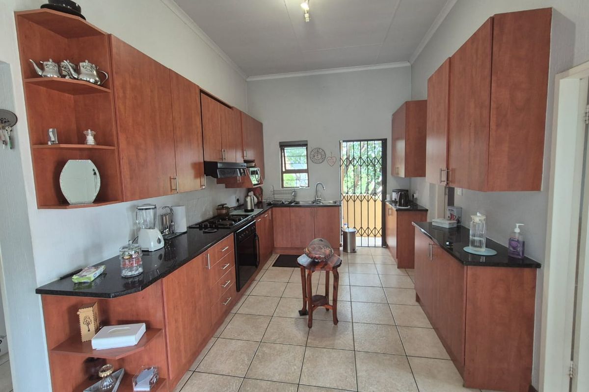 A functional kitchen featuring wood-veneer cabinetry, dark granite countertops, a built-in oven, and a gas hob, with direct access to the exterior.