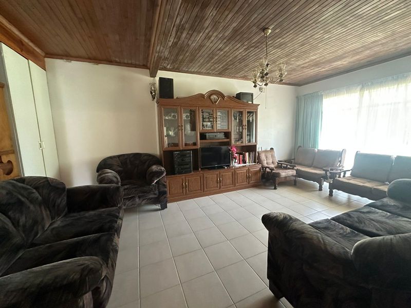 Spacious living room featuring a timber-clad ceiling, ceramic tiled flooring, and built-in cabinetry, offering a dated aesthetic ready for modern updates.