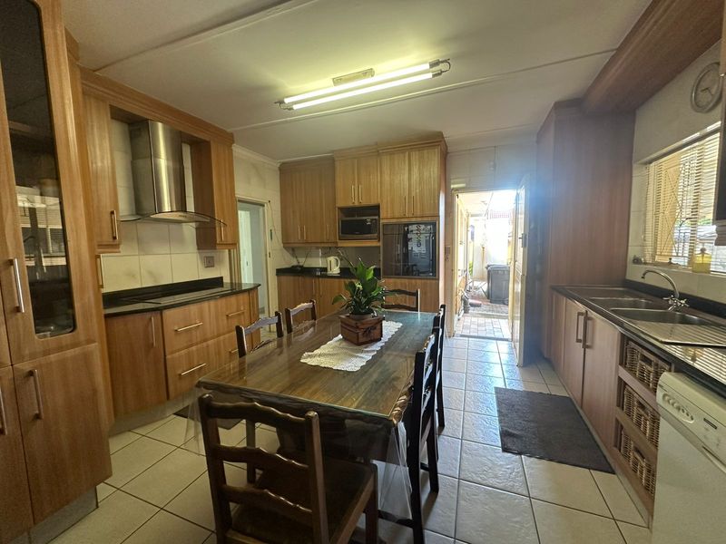 A functional kitchen featuring wooden cabinetry, granite countertops, built-in oven, and stainless steel extractor fan, with direct access to an outdoor area.
