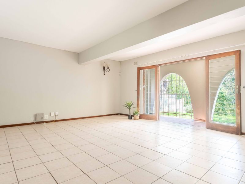Spacious, light-filled living area featuring neutral ceramic floor tiles and large timber-framed sliding doors providing direct access to the outdoor patio area.