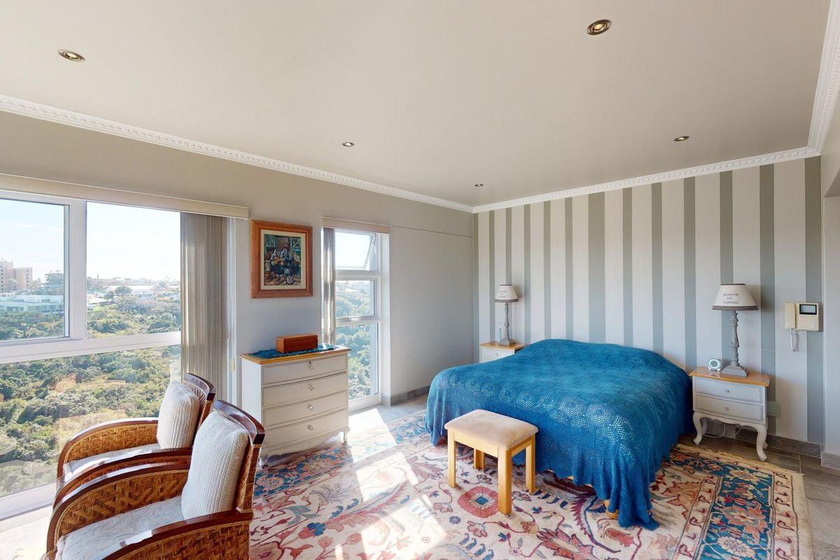 Spacious bedroom featuring large windows with panoramic views, recessed downlights, and neutral striped wallpaper.