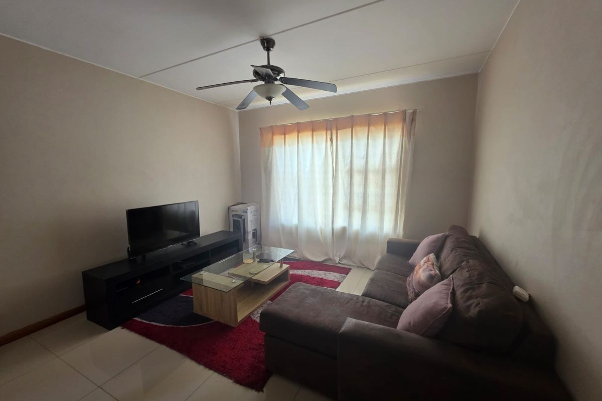 A comfortable living room featuring tiled flooring and a ceiling fan, providing a functional space for relaxation.