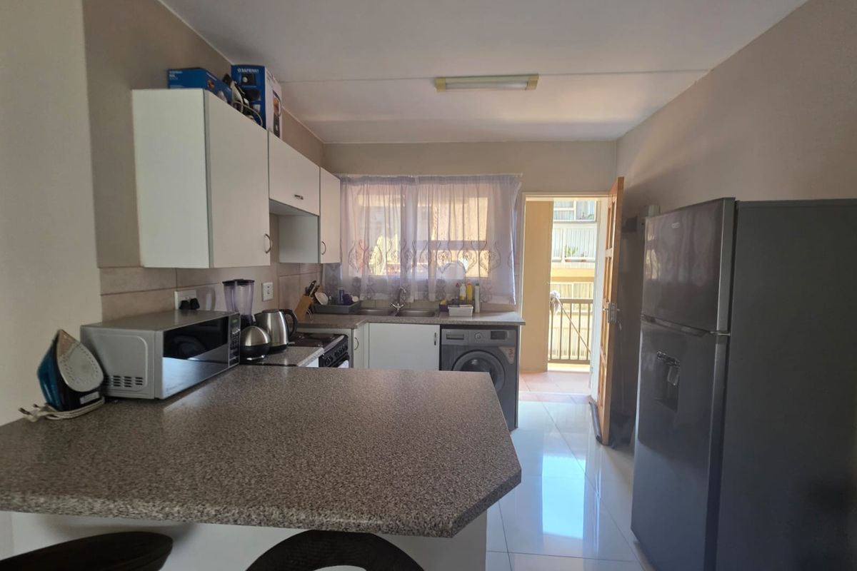 Functional kitchen featuring laminate countertops, tiled backsplash, built-in cabinetry, and direct access to an outdoor balcony area.
