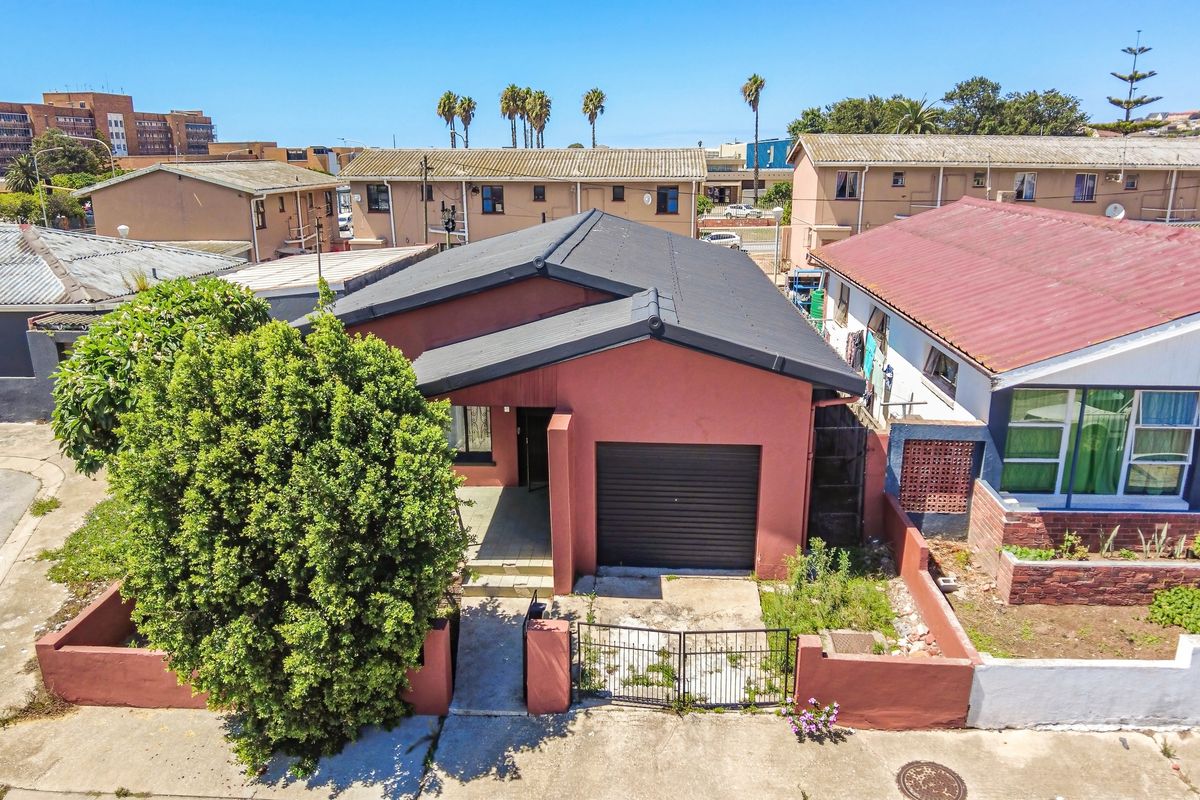 Aerial view of a detached house featuring a single garage, front entrance, and perimeter boundary walls in a residential neighborhood setting.