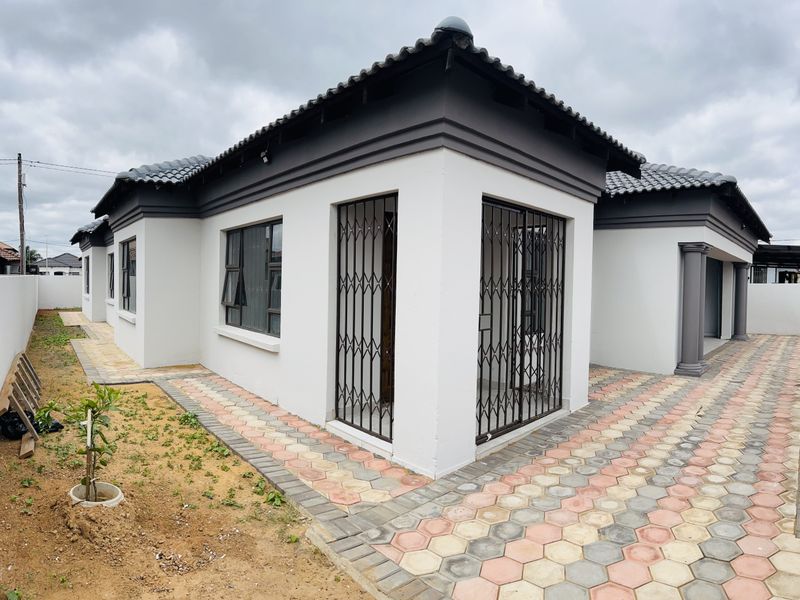 A well-maintained rear exterior view of the house featuring a tiled roof, paved pathways, and secure metal gates on the windows and doors.