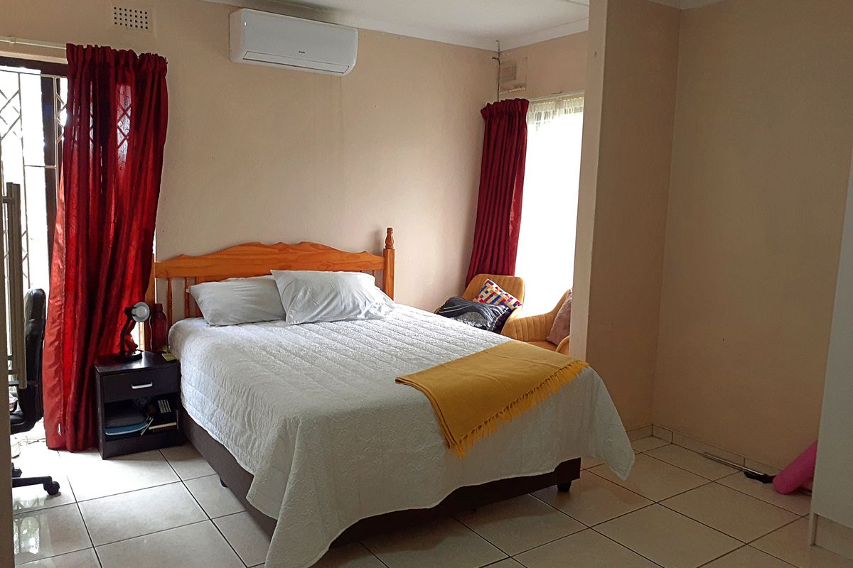 A bedroom featuring tiled flooring, an air conditioning unit, and access to an outdoor area through a security gate.