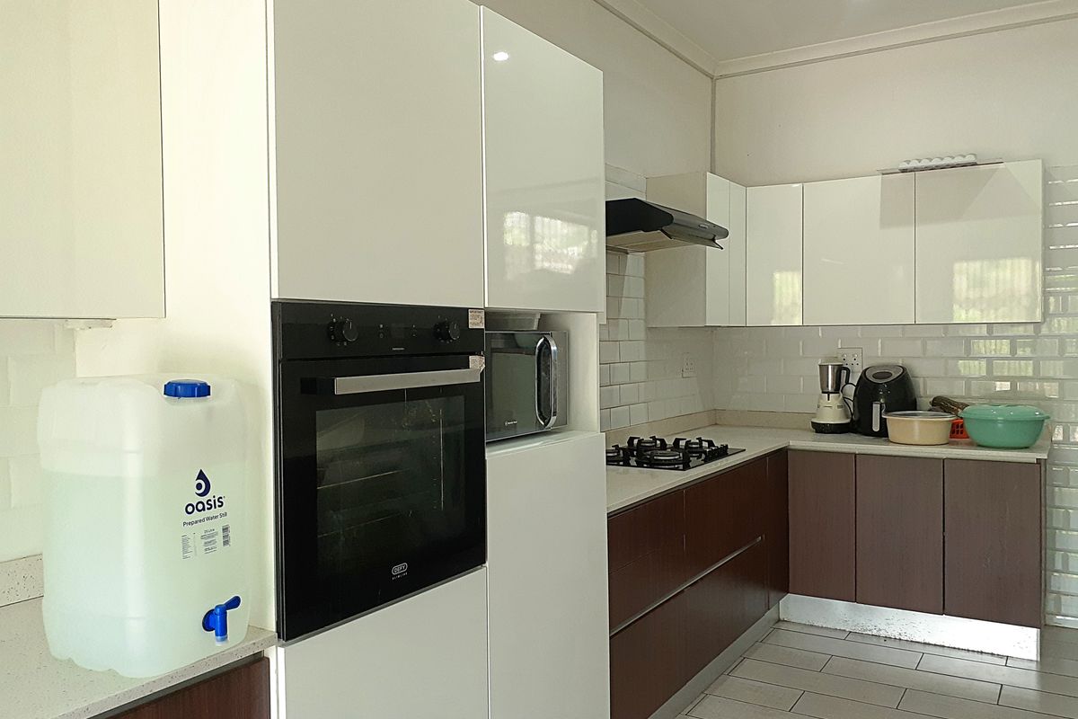 Modern kitchen featuring high-gloss white and dark wood cabinetry, stone countertops, subway tile backsplash, and integrated stainless steel appliances.