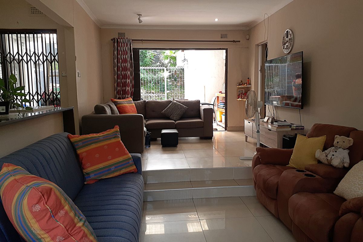 Spacious living area featuring tiled flooring, recessed lighting, and a raised floor section leading to a sliding glass door with outdoor access.