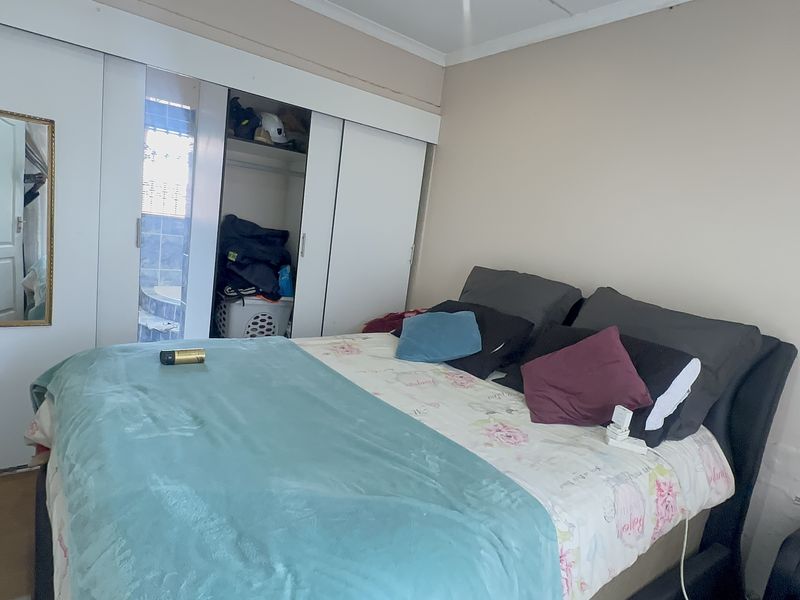 A bedroom featuring a built-in sliding door wardrobe, requiring some wall repairs and cosmetic updates to improve the overall finish.