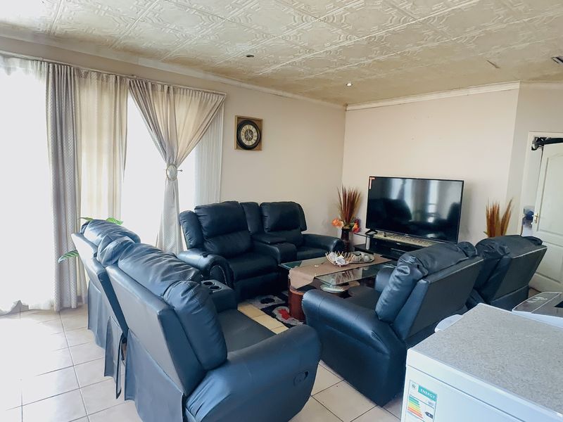 A comfortable living room featuring tiled flooring, a textured ceiling, and a sliding glass door providing natural light.