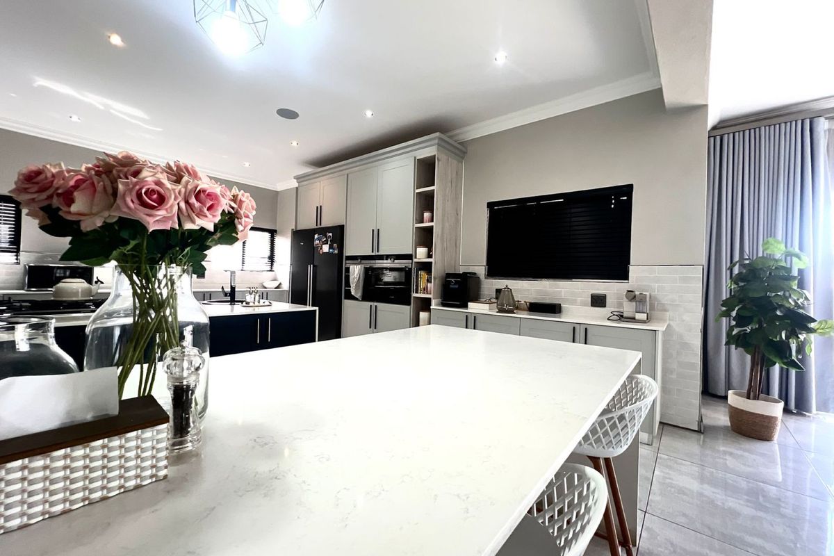 Modern kitchen featuring a large central island with stone countertops, built-in cabinetry, integrated appliances, and sleek tiled flooring.