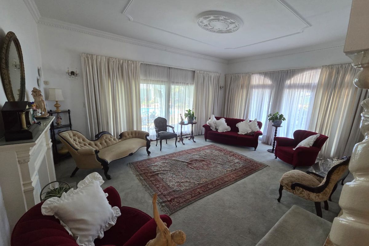 Spacious living room featuring a classic fireplace mantel, decorative ceiling rose, and large sliding glass doors providing natural light and garden access.