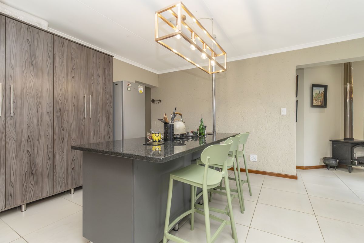 Modern kitchen featuring a central island with granite countertops, ample built-in cabinetry, and a cozy wood-burning stove in the adjacent living area.