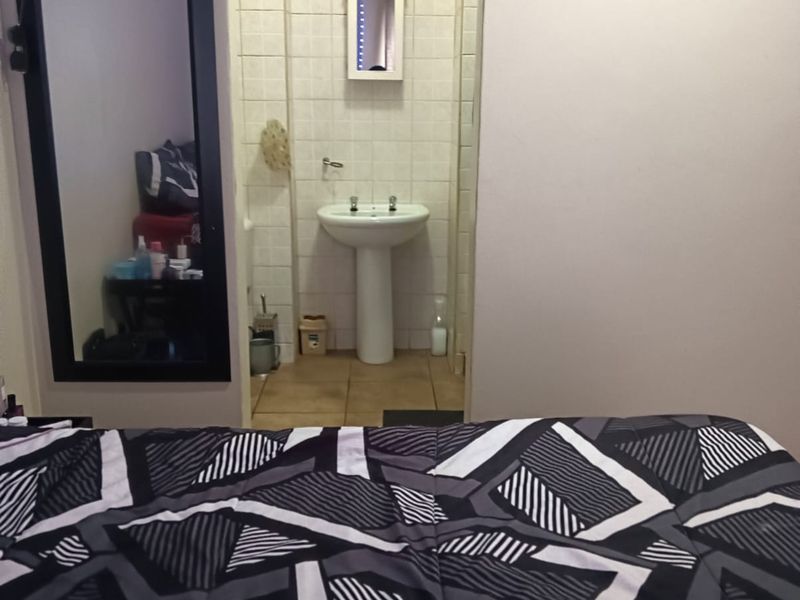 A view from the bedroom into an en-suite bathroom featuring a pedestal basin and tiled finishes.