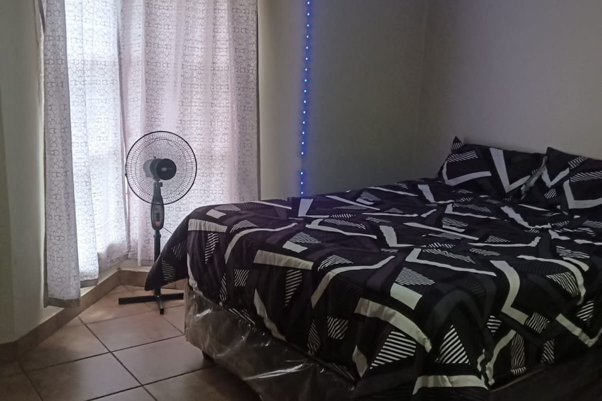 A bedroom featuring tiled flooring and window curtain rails, illuminated by ambient LED strip lighting.