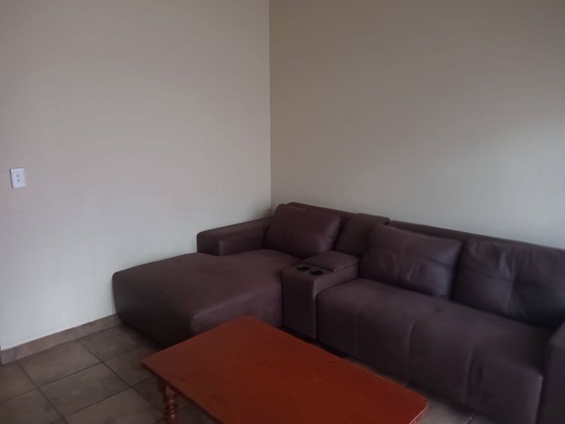 A living room area featuring neutral wall finishes and tiled flooring, providing a functional space for relaxation.