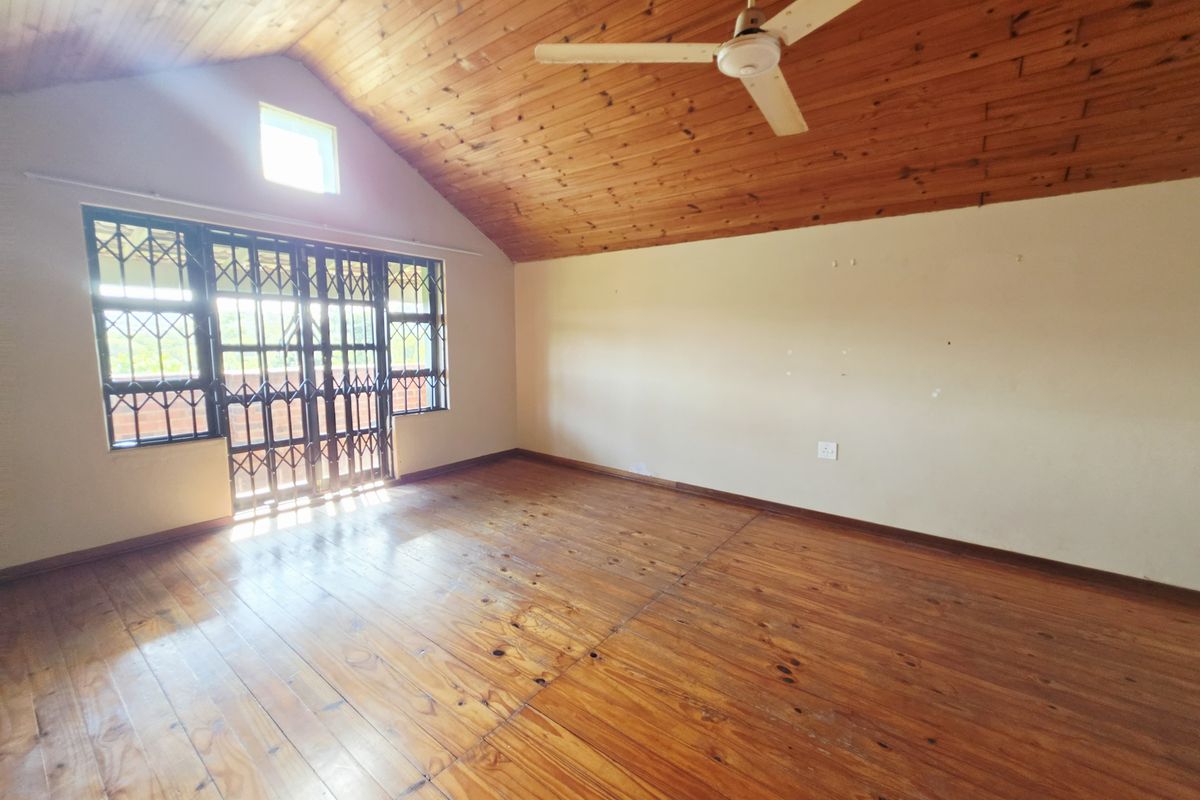 Spacious bedroom featuring vaulted timber ceilings, polished timber flooring, and secure access to an outdoor area.