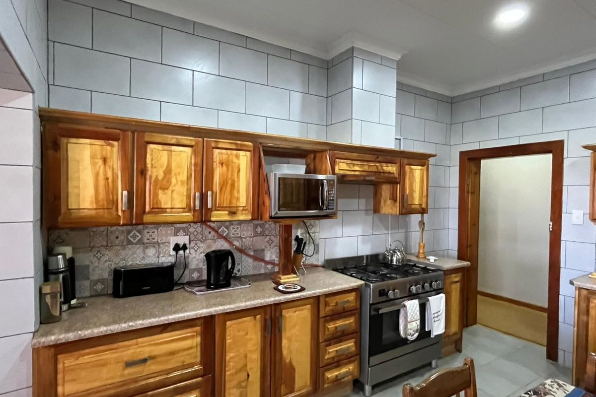 A functional kitchen featuring wooden cabinetry, laminate countertops, a gas stove, and a built-in microwave with tiled wall finishes.