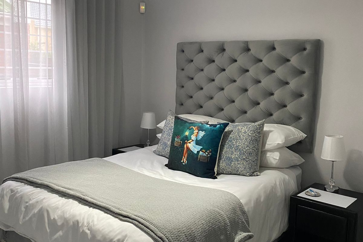 A well-maintained bedroom featuring neutral wall tones, tiled flooring, and a modern pendant light fixture.