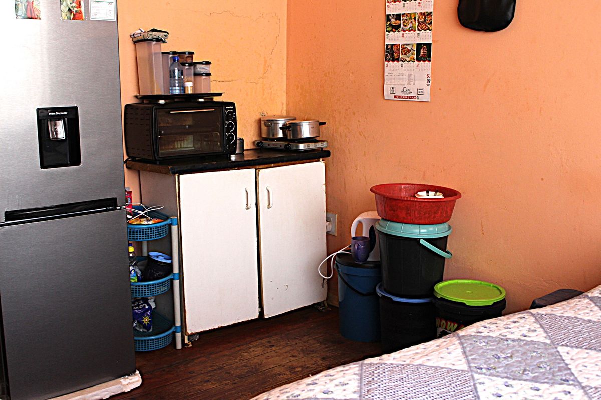 A small kitchen area featuring basic built-in cabinetry, a countertop, and timber flooring, currently showing signs of wear and requiring maintenance.